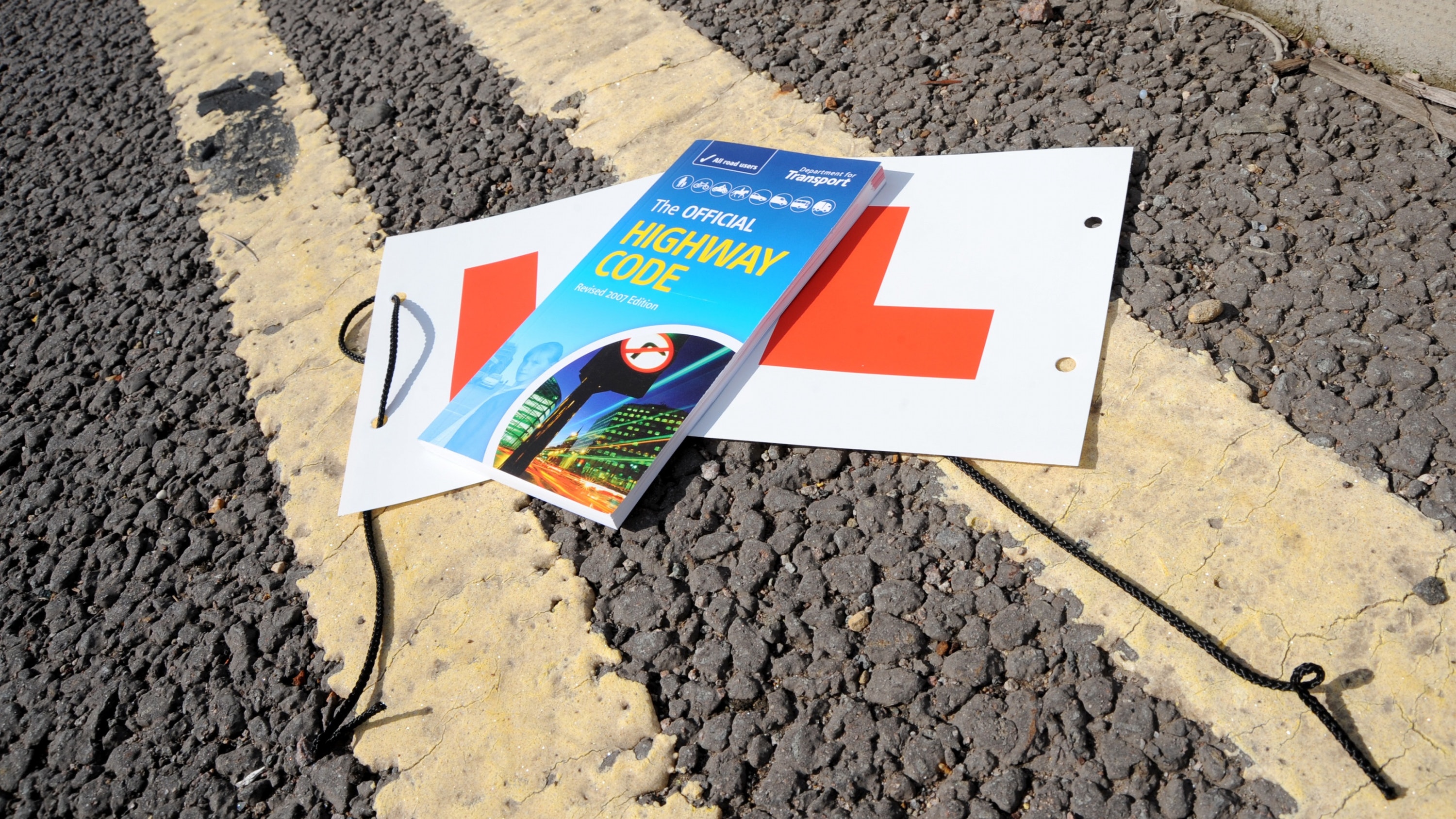 Learner L plates and highway code on a double yellow line